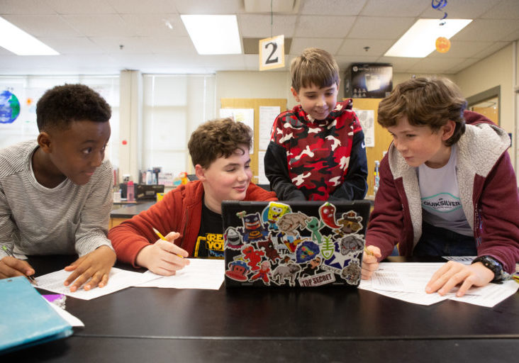 Sixth-graders work together on a science project about weather disasters.